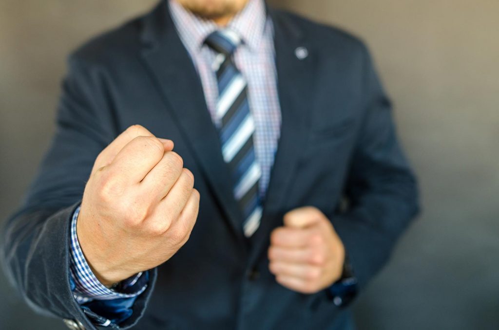 Man in suit holding clenched fists in anger.