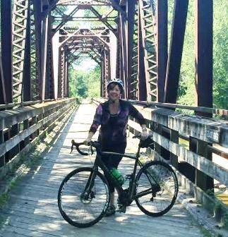 Katie Watt standing on a bridge with a bicycle.